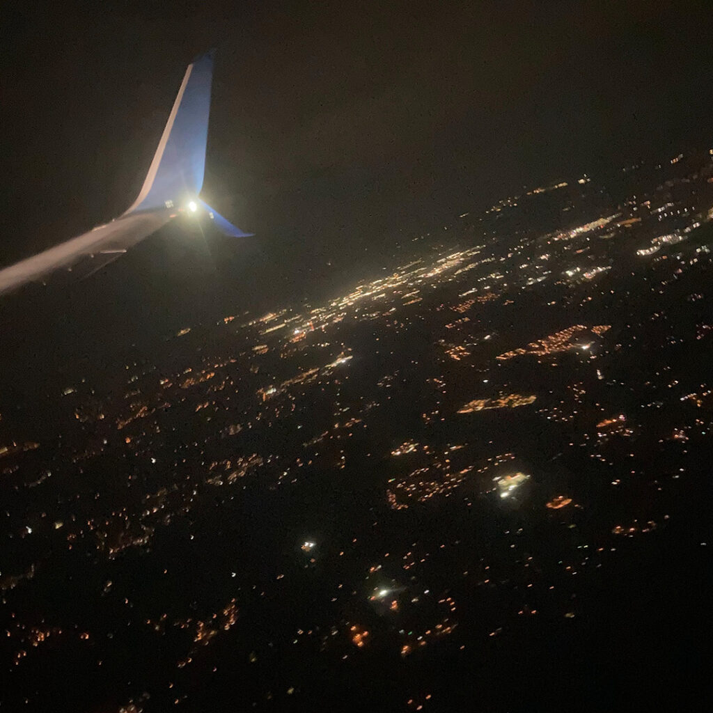 Nighttime view of city lights from a plane window.