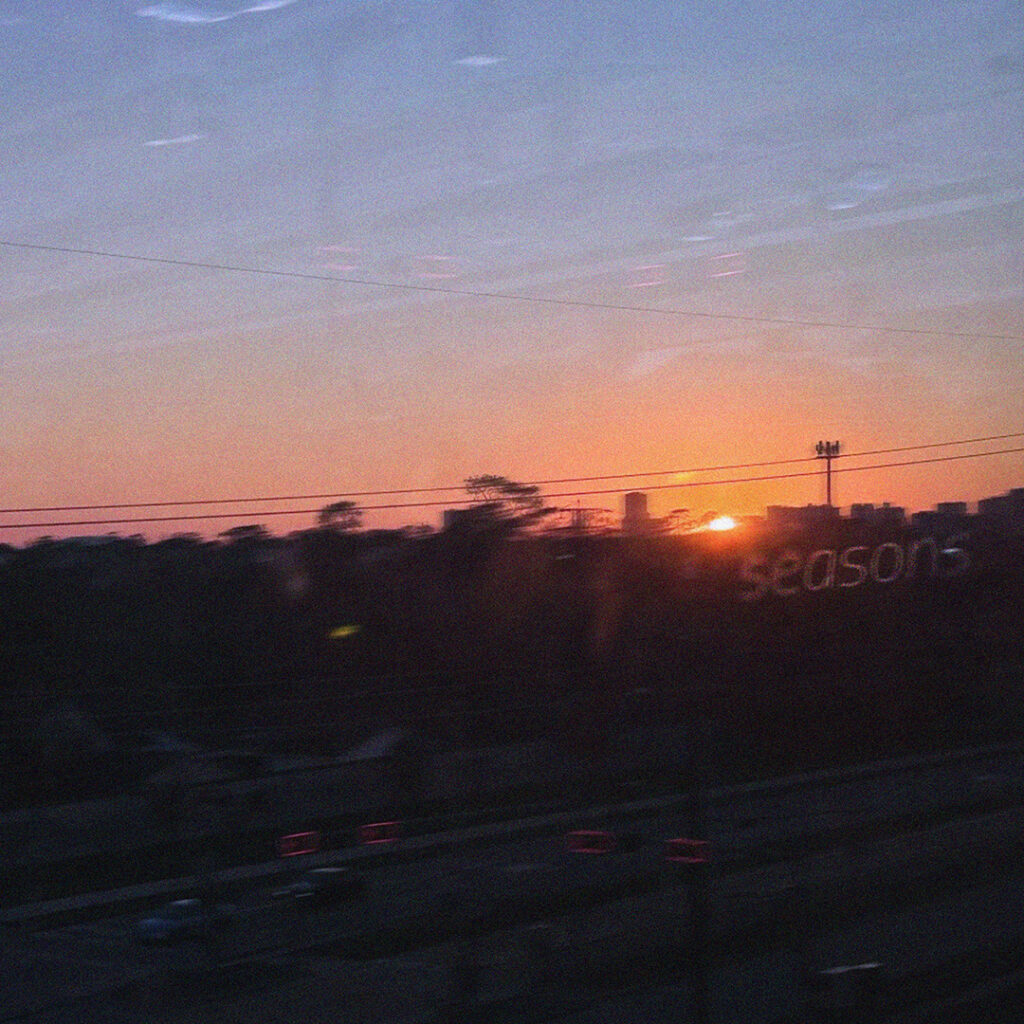 Blurry sun setting against city skyline with text: seasons.