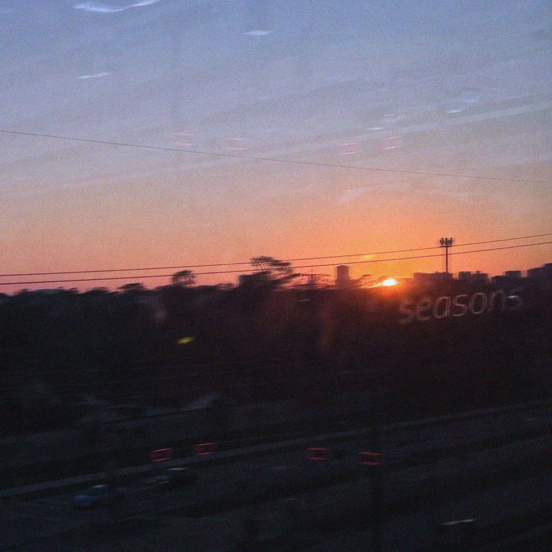 Blurry sun setting against city skyline with text: seasons.